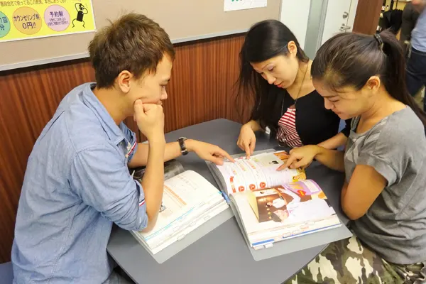 three students studiying on a desk